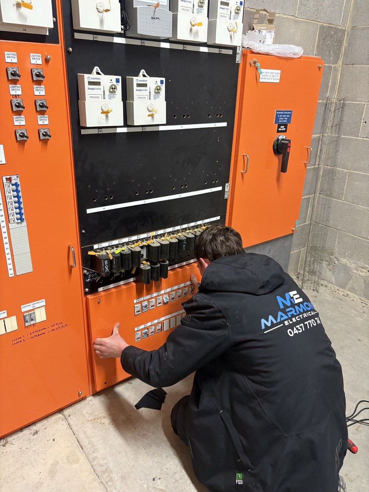 Electrician working inside a large commercial switchboard