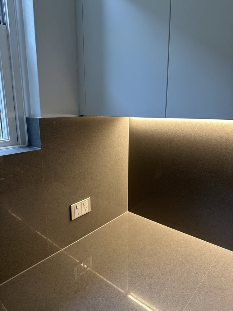 Concealed under-cabinet LED strip lighting in a modern kitchen by Marmont Electrical